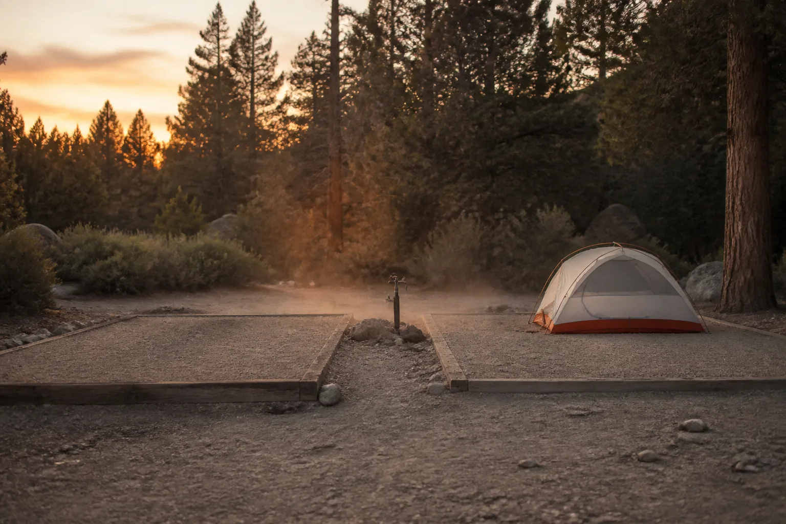 Two neighbouring tent pads on packed earth at dusk, one empty and one holding a low dome tent, a shared water spigot between them, evening light catching dust above the gravel, a forest edge closing the background, 1600x900